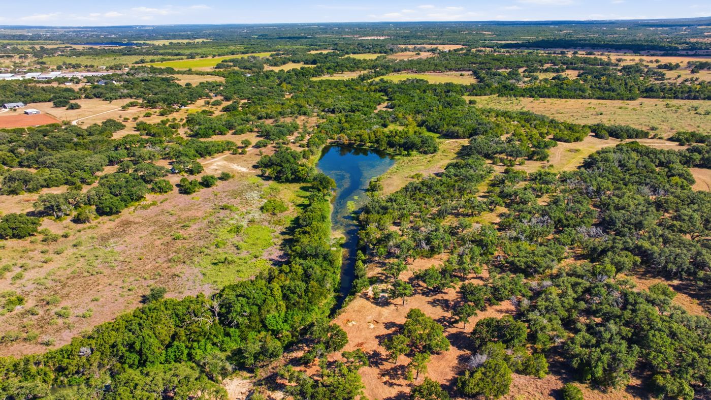 Aerial view of the existing pond and creek winding through mature oaks